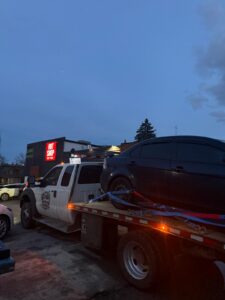 Jim Towing flatbed loading a vehicle at dusk in Calgary