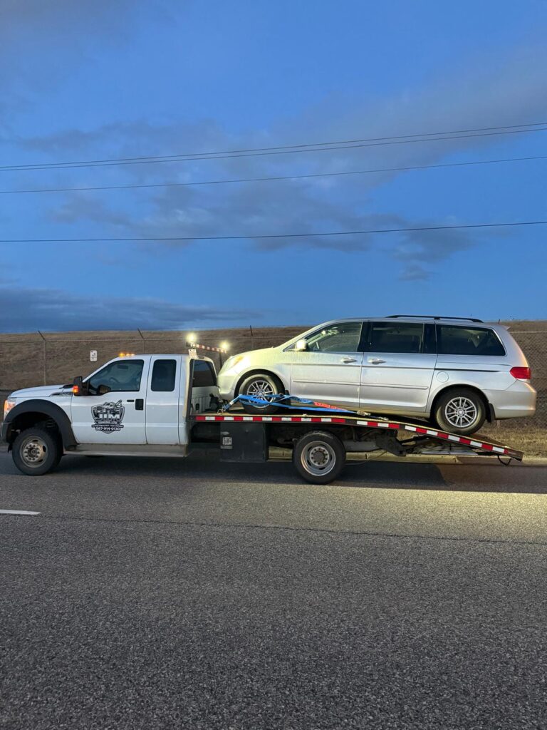 Minivan secured on a Jim Towing flatbed at sunset