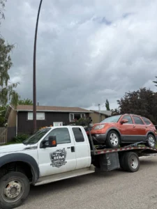 Red SUV on a Jim Towing flatbed in a Calgary neighbourhood