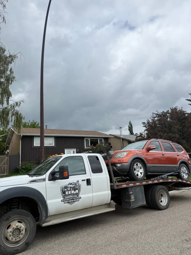 Red SUV on a Jim Towing flatbed in a Calgary neighbourhood