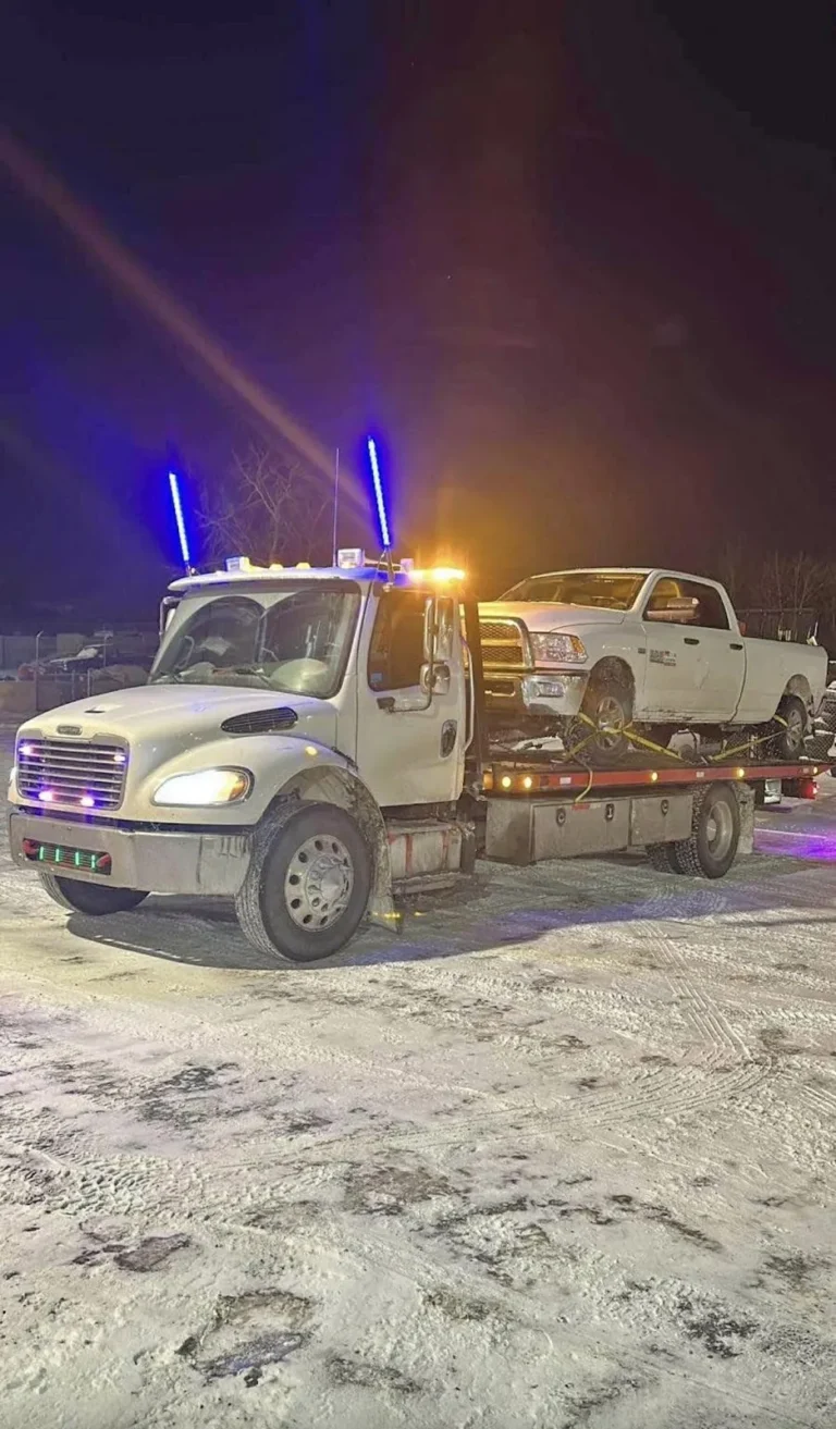 Jim Towing heavy flatbed hauling a pickup truck at night in winter