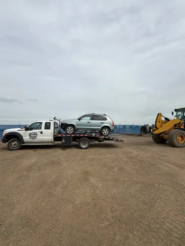 Jim Towing flatbed transporting a vehicle across Alberta