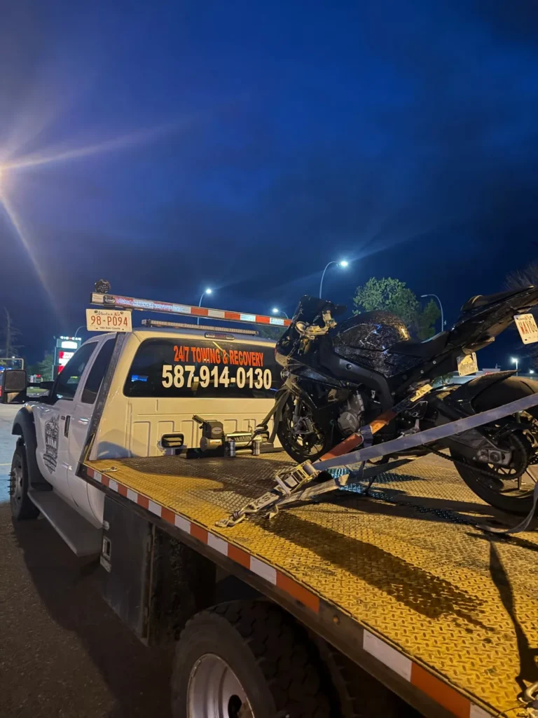 Motorcycle secured on a Jim Towing flatbed at night in Calgary
